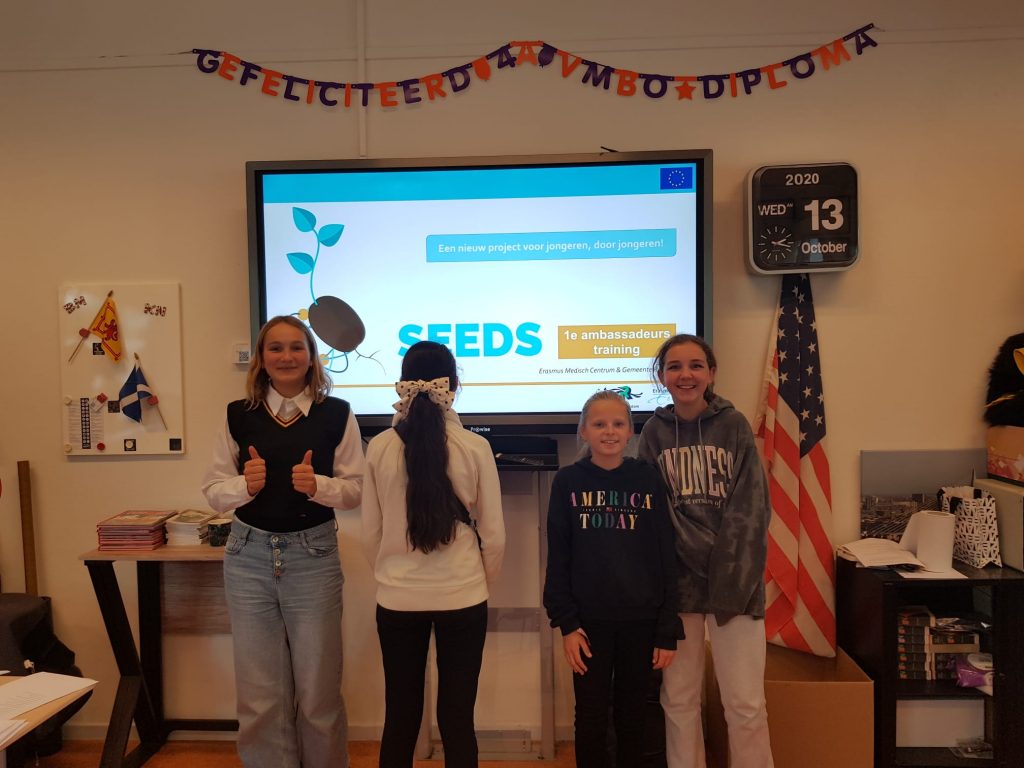 Teenagers in the Dutch Ambassador Training standing in front of the SEEDS logo. 