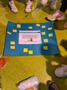 Feet of teenagers standing around a large blue A0 landscape poster with postits.