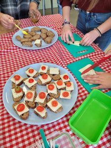 Teenagers preparing a plate of sandwiches with cheese and tomatoes